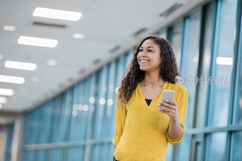 一名年轻女子在走廊里给朋友发短信