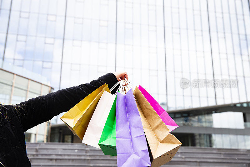 女人拿着许多购物袋在时尚精品店，闪光。消费主义和销售观念