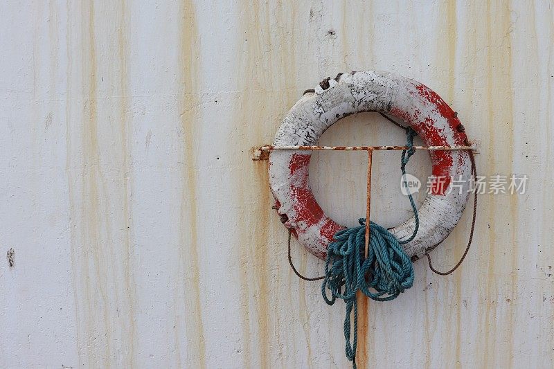 脏兮兮的旧救生圈挂在沾满白色污迹的港湾墙上