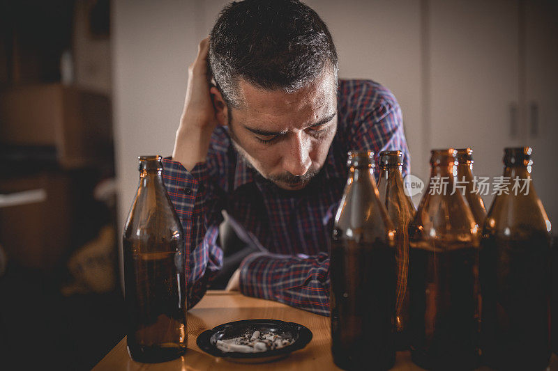 年轻悲伤的醉酒男子喝啤酒和酒精感到浪费，孤独和绝望的痛苦和情绪压力。人与酗酒、上瘾和男人抑郁的概念。