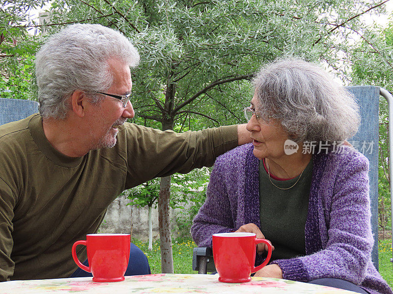 一对活跃的老夫妇在房子的后院喝清晨咖啡