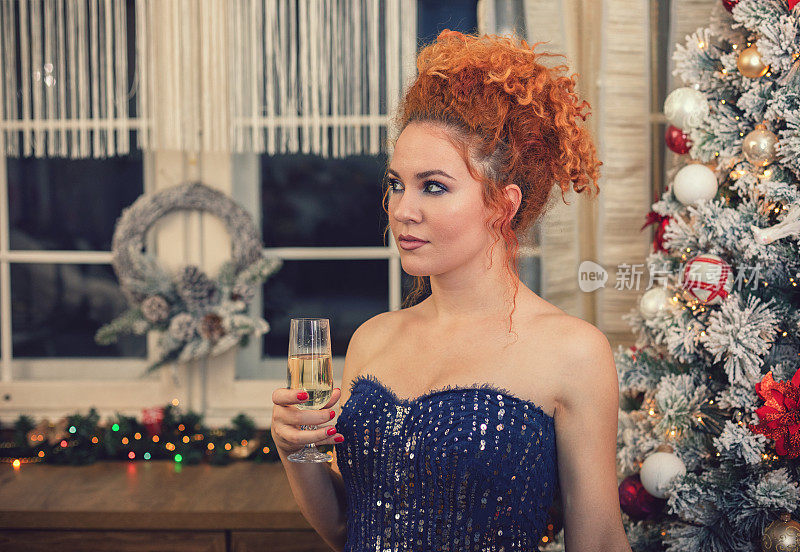 庆祝的时候了。漂亮的女孩拿着香槟站在圣诞树前