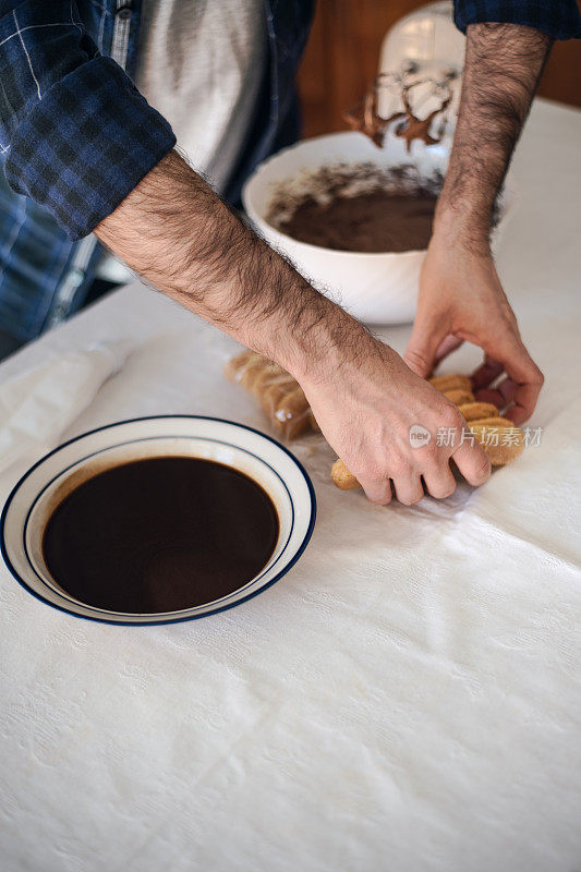 检疫烹饪:一名男子用电动搅拌器、巧克力、饼干和咖啡煮提拉米苏