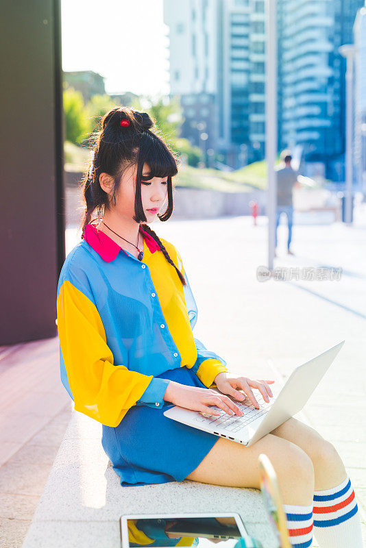 年轻美丽的亚洲千禧女不墨守成规的户外城市背光使用电脑敲击键盘