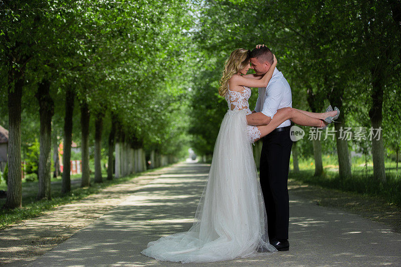 美丽的新婚夫妇在户外的汽车前面