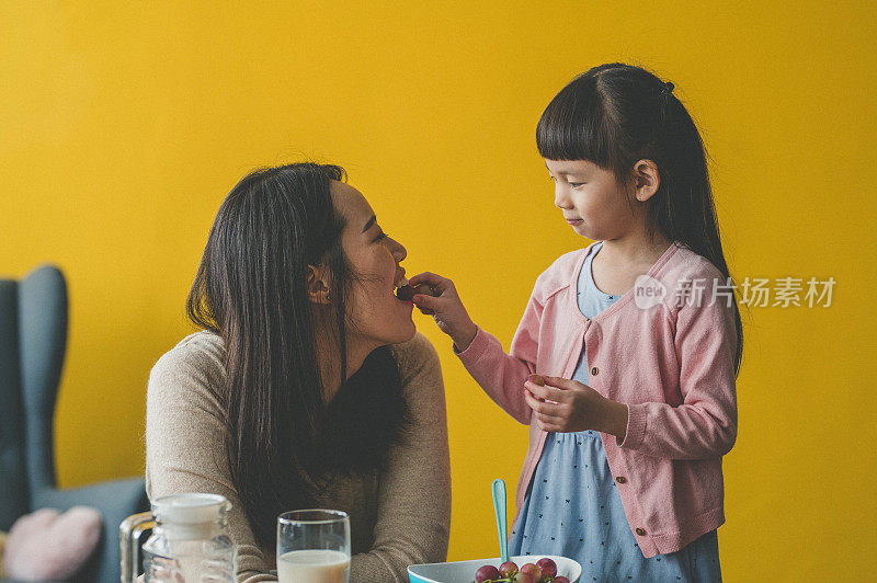 可爱的女儿在客厅给妈妈喂葡萄