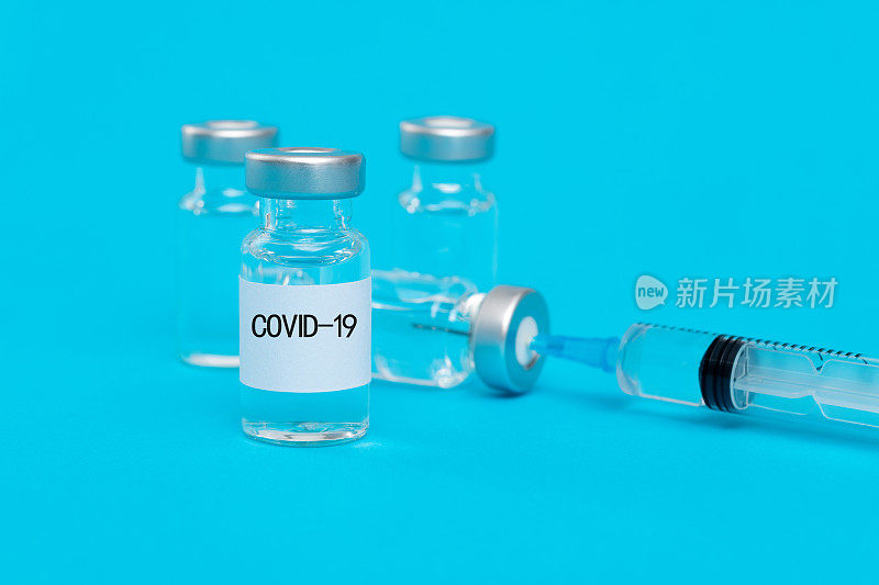 蓝色背景为注射器和Covid-19疫苗瓶
