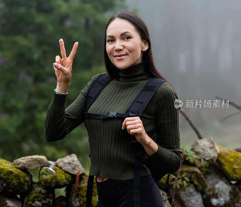 背着背包的年轻女子徒步旅行者在户外的山区旅行