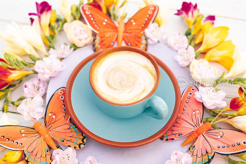 蓝色杯，波西米亚风格的奶油咖啡，小苍兰，樱花和蝴蝶