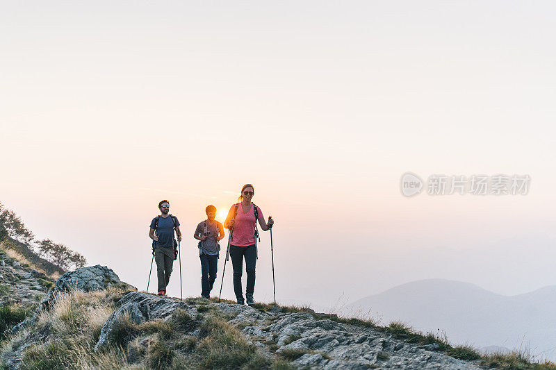 朋友们在日出时沿着阳光明媚的山脊徒步旅行