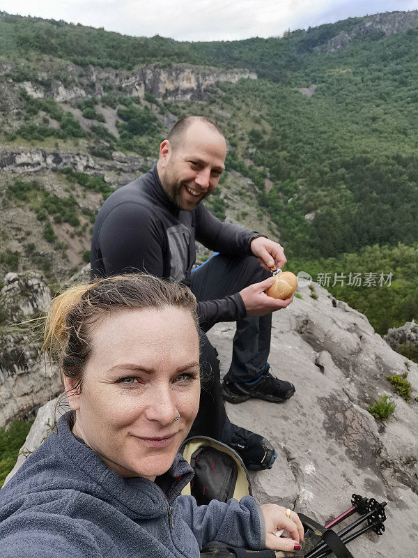 微笑情侣在山间徒步旅行时休息的自拍