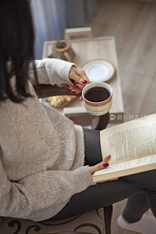 年轻女子一边喝咖啡一边看书