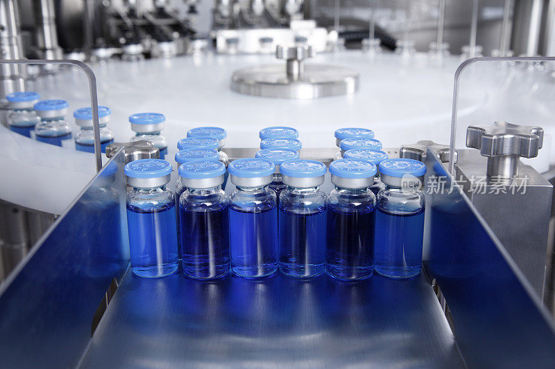 在生产的玻璃瓶托盘上有一个自动液体分配器，用于灌装抗菌病毒药物、抗生素和疫苗的流水线