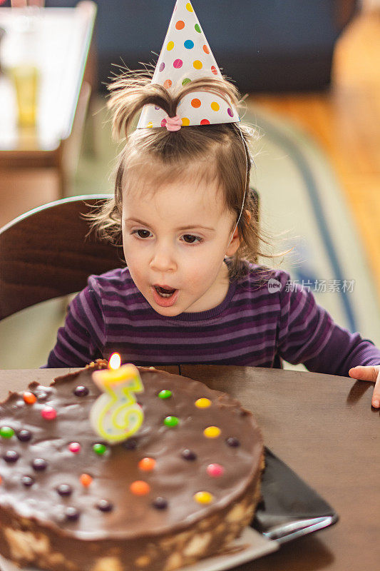 可爱的小女孩站在生日蛋糕前