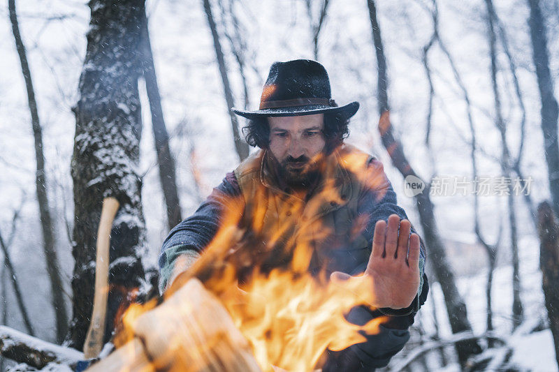 清晨，在白雪皑皑的森林里，年轻人在篝火旁放松