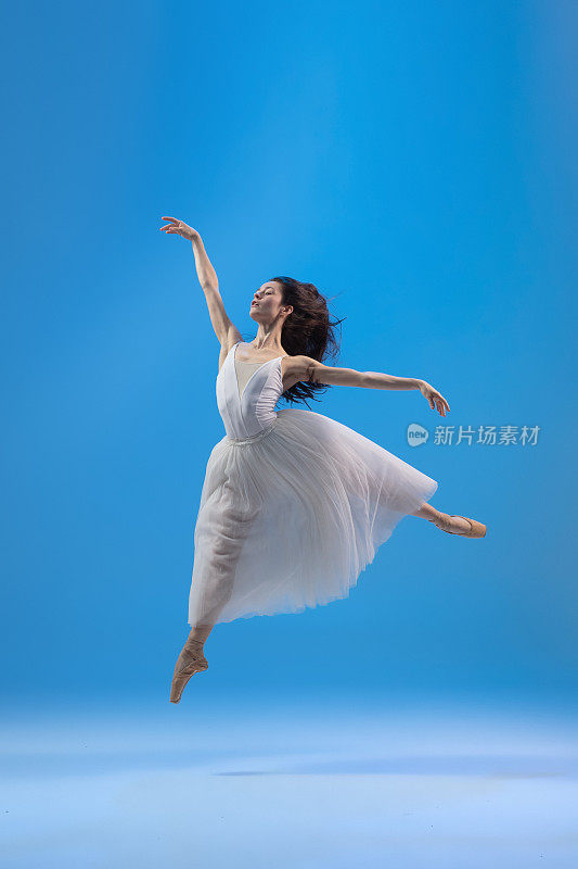 年轻和优雅的芭蕾舞者孤立在蓝色演播室背景。艺术，运动，动作，灵活性，灵感概念。
