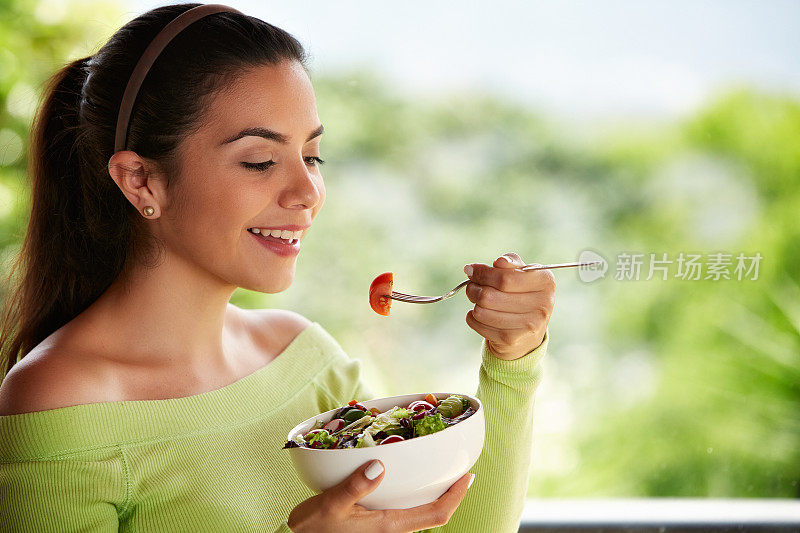 一个西班牙可爱的年轻女子在午餐吃素食沙拉的特写