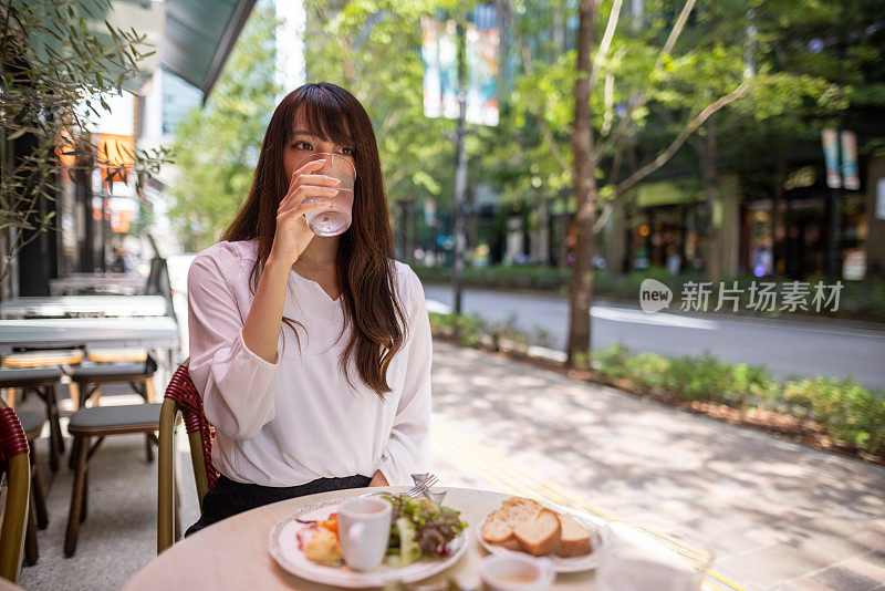 一名日本女子在阶梯咖啡馆午餐时喝水