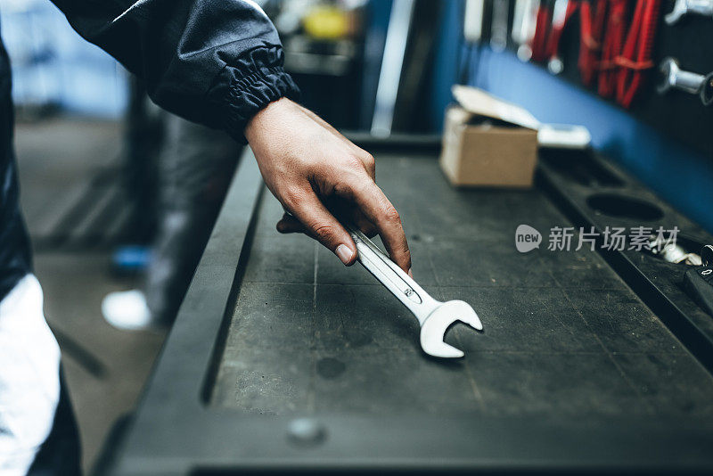 陌生人，一名男工人从墙上拿工具修理自行车或汽车。