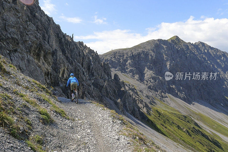 女人沿着阳光明媚的自行车道骑山地车