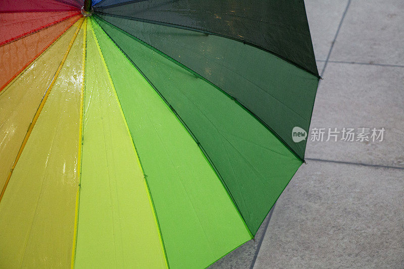 雨点落在彩虹伞上，天以自然为背景