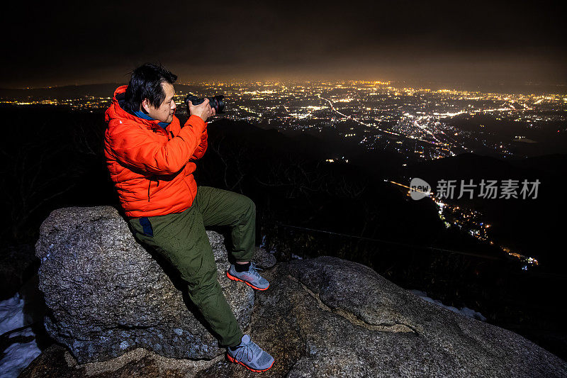 一名摄影师在山顶上拍摄夜晚的城市景色