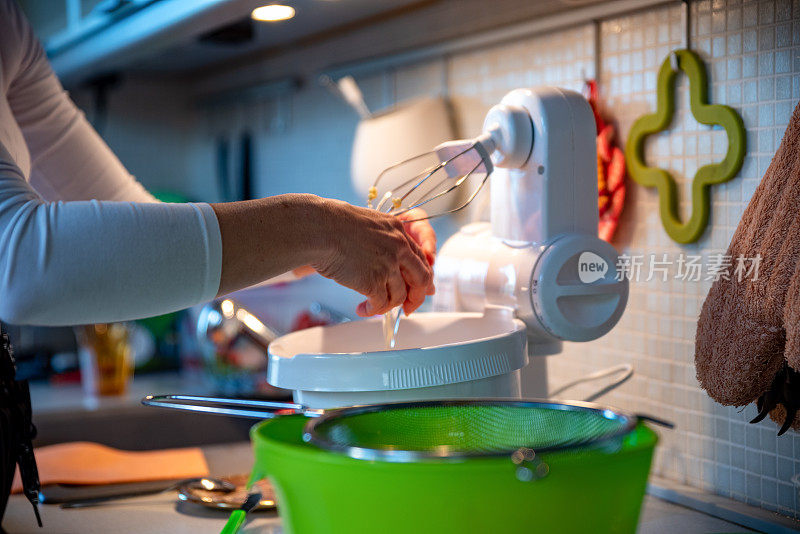 女人把鸡蛋打到立式搅拌机里做甜甜圈面团