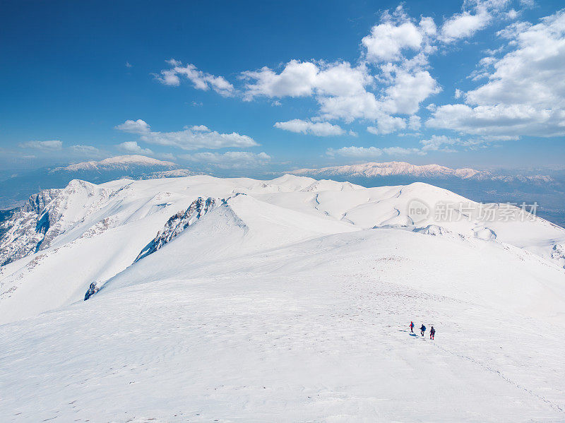 无人机拍摄成功的登山队伍在冬季在高海拔雪山峰顶的山脊上排排攀登