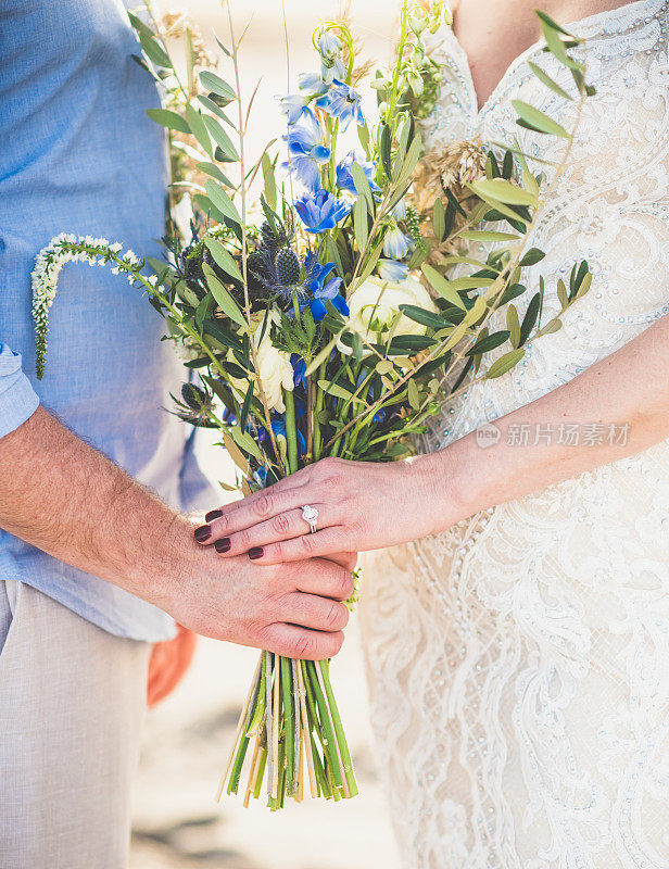 婚礼细节，新郎和新娘穿着结婚礼服，戴着钻石戒指，手持美丽的花束的特写