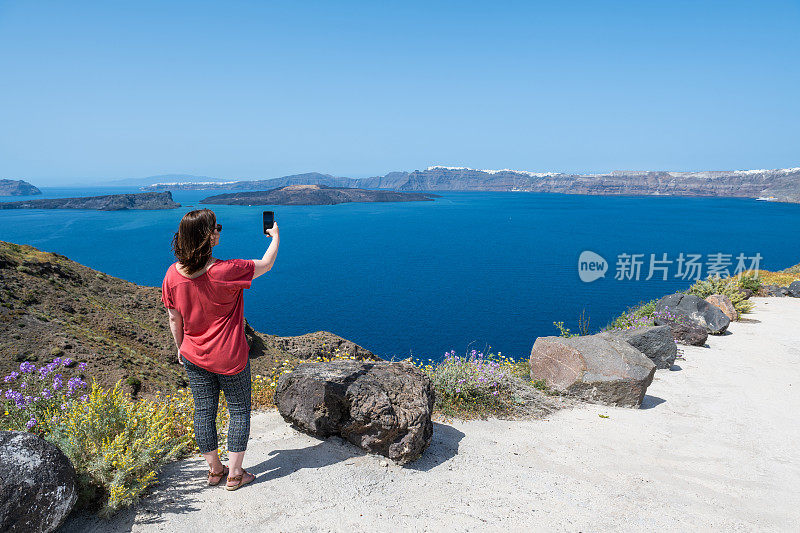 一个女人站在平静海湾的海角上