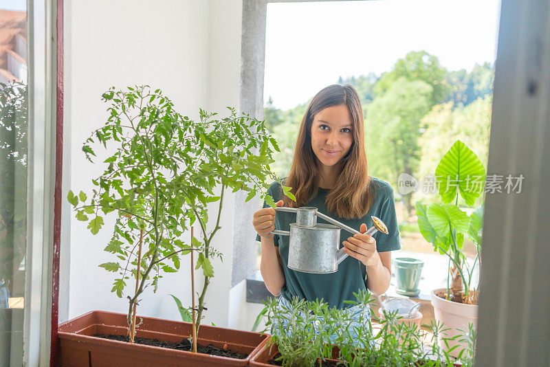 一名年轻女子在公寓露台上给植物浇水