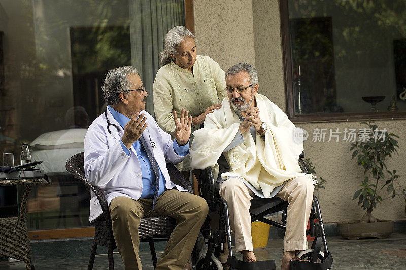 医生在家中与轮椅上的残疾老人讨论