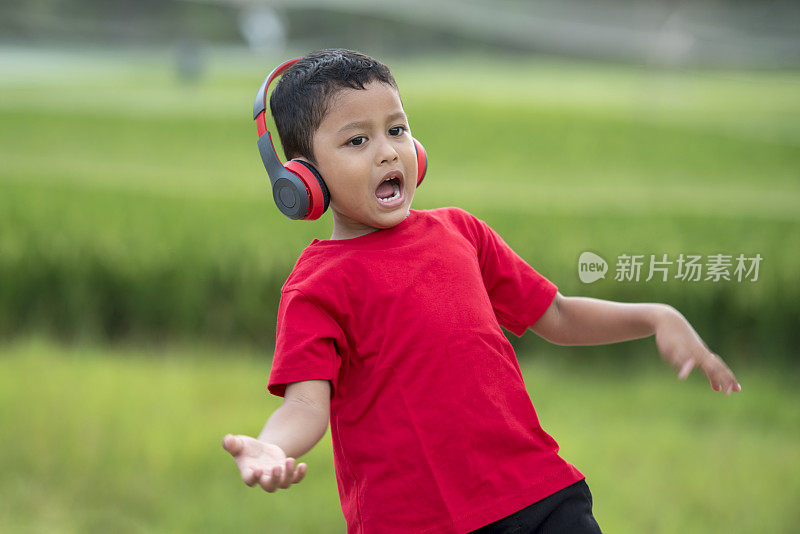 蹒跚学步的男孩用耳机听音乐