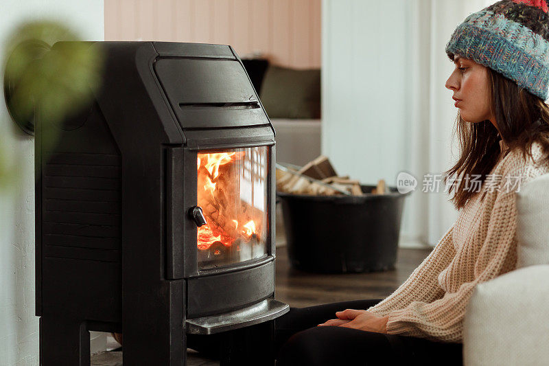 一个女人坐在壁炉旁取暖