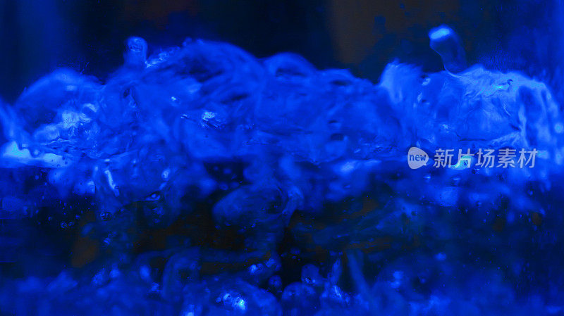 模糊的背景照片的开水在茶壶与蓝色背光，图像的水气泡，为背景的想法