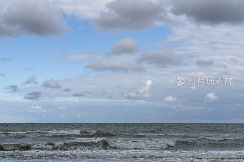 在一个晴朗的夏日，俄罗斯加里宁格勒地区的库尔斯沙嘴，暴风雨中的波罗的海映衬着多云的天空