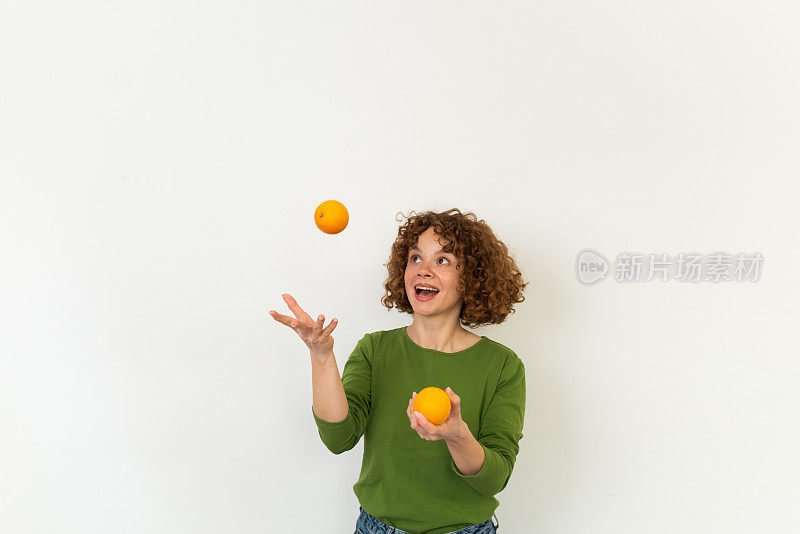 画室里一个漂亮的红发女孩摆弄橘子的肖像