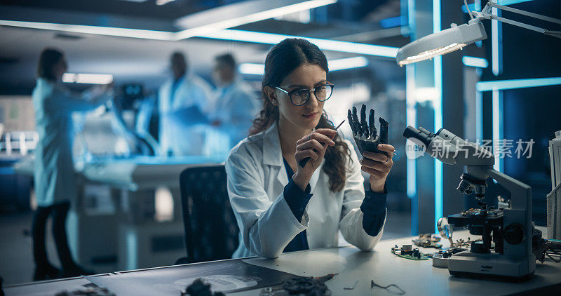 女工程师正在修理一个高科技仿生手部件。工业机器人专家穿着实验室大褂在科技工厂设施中研究移动人工智能机器人