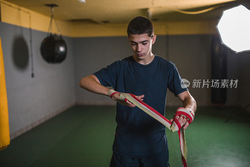 一名年轻的男拳击手在戴上拳击手套之前，用一块布包裹双手，这有助于减少拳击对手时的冲击力，并有助于防止拳击受伤