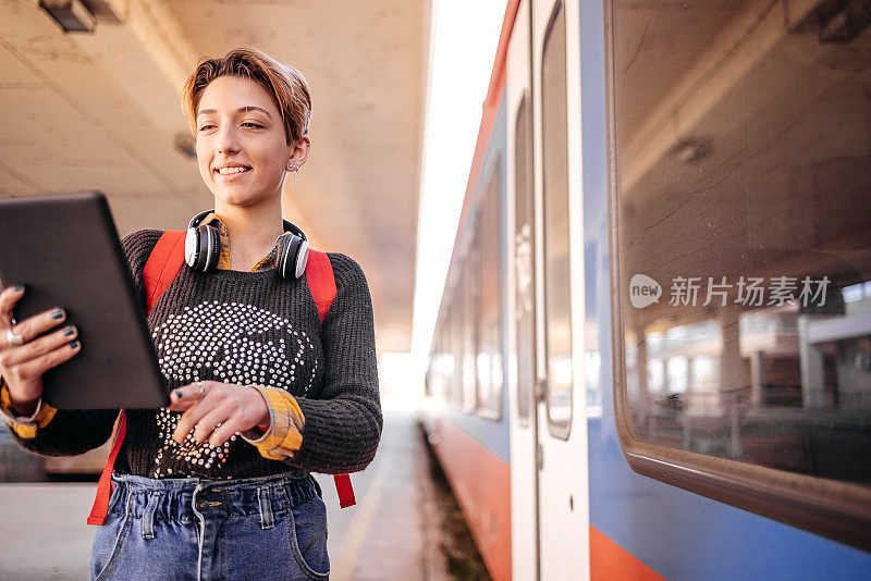 年轻女子在上班的路上等火车时使用数码平板电脑