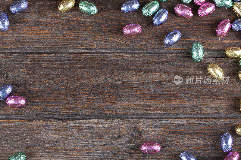 糖果巧克力复活节彩蛋组成框架在质朴的木制背景