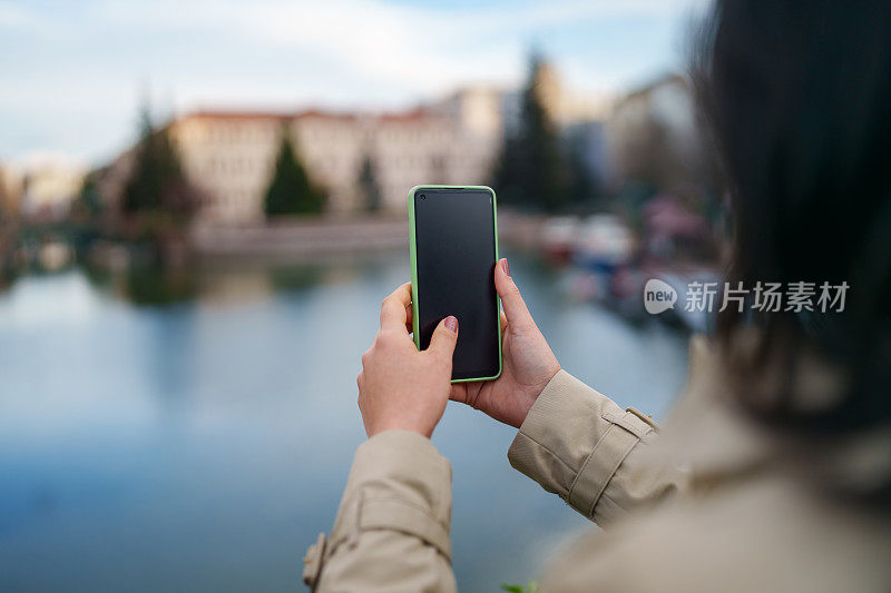 亚洲女人用手机拍照，在城里旅行。