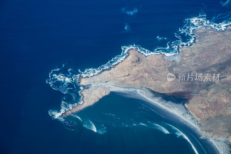 几组太平洋海浪撞击一小块陆地，造成波浪弯曲。下加利福尼亚南部，墨西哥。波变浅。