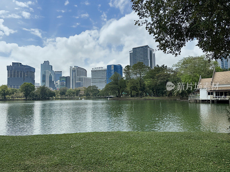 城市景观摩天大楼天际线的特写图像，在湖对面，隆皮尼公园，帕图姆湾区，曼谷，泰国，多云晴朗的蓝天