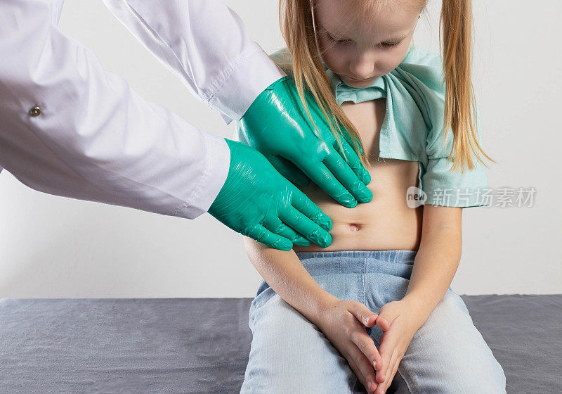 一位治疗师医生的手在触摸一个七岁小女孩的腹部，看她的器官是否疼痛。腹部器官发炎，消化不良，肠子疼痛，特写