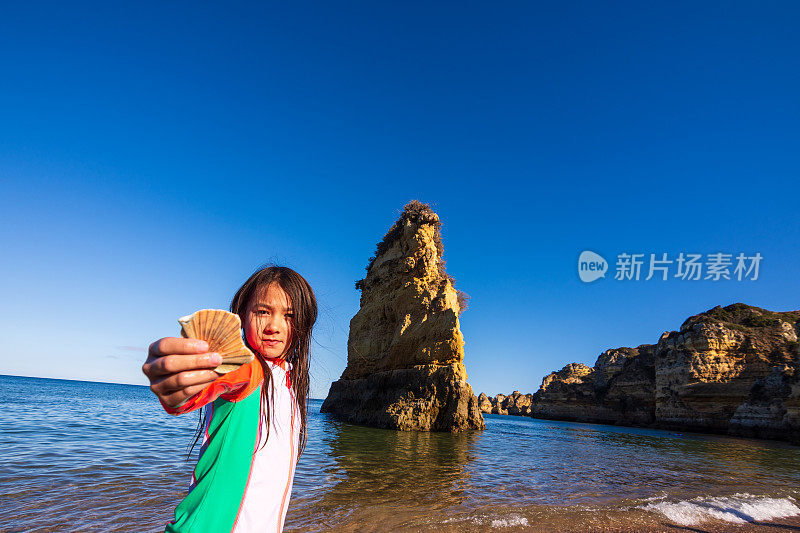 女孩展示她在葡萄牙阿尔加维普拉亚多纳阿纳海滩上发现的贝壳