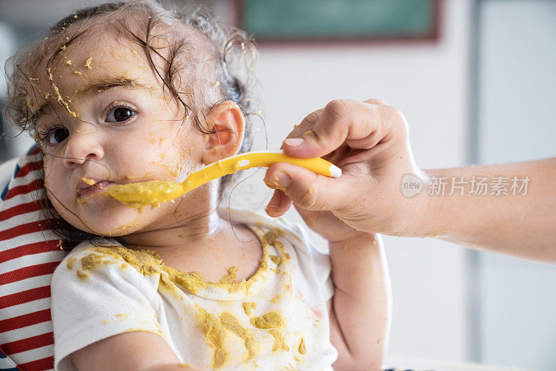 女婴坐在喂食椅上吃婴儿食品