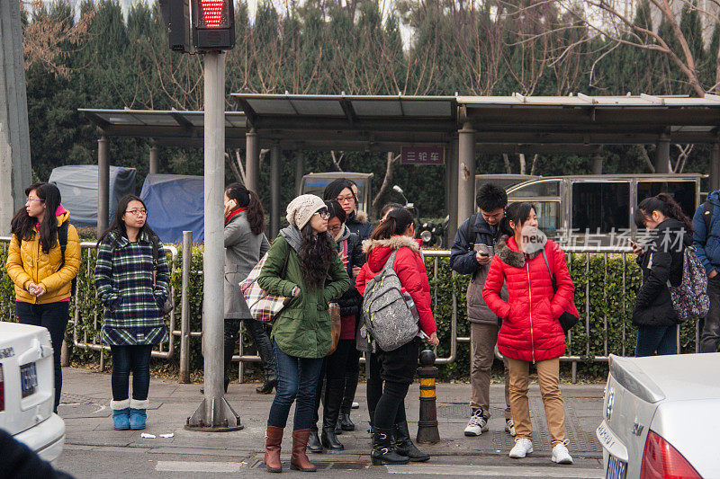 在中国北京的一个工作日的早晨，人们在汽车站等车。