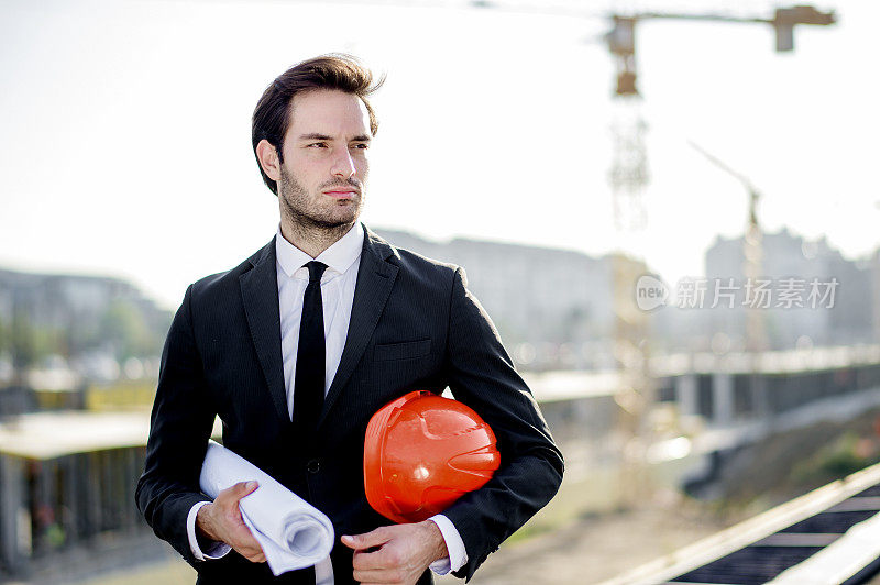 年轻的建筑工程师带着工程和安全帽