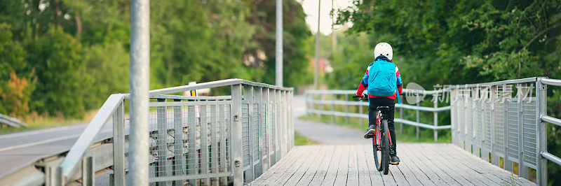 孩子背着背包在学校附近的公园里骑自行车